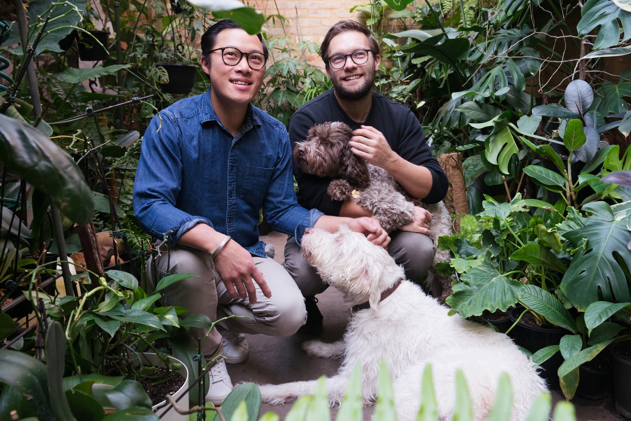 2 people and their dogs happily standing in between dog friendly plants